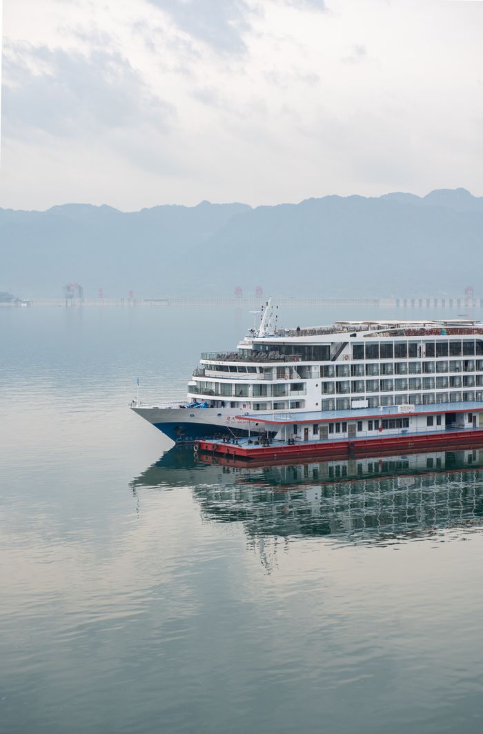 home-img Luxury cruise ship navigating serene waters with mountain backdrop.