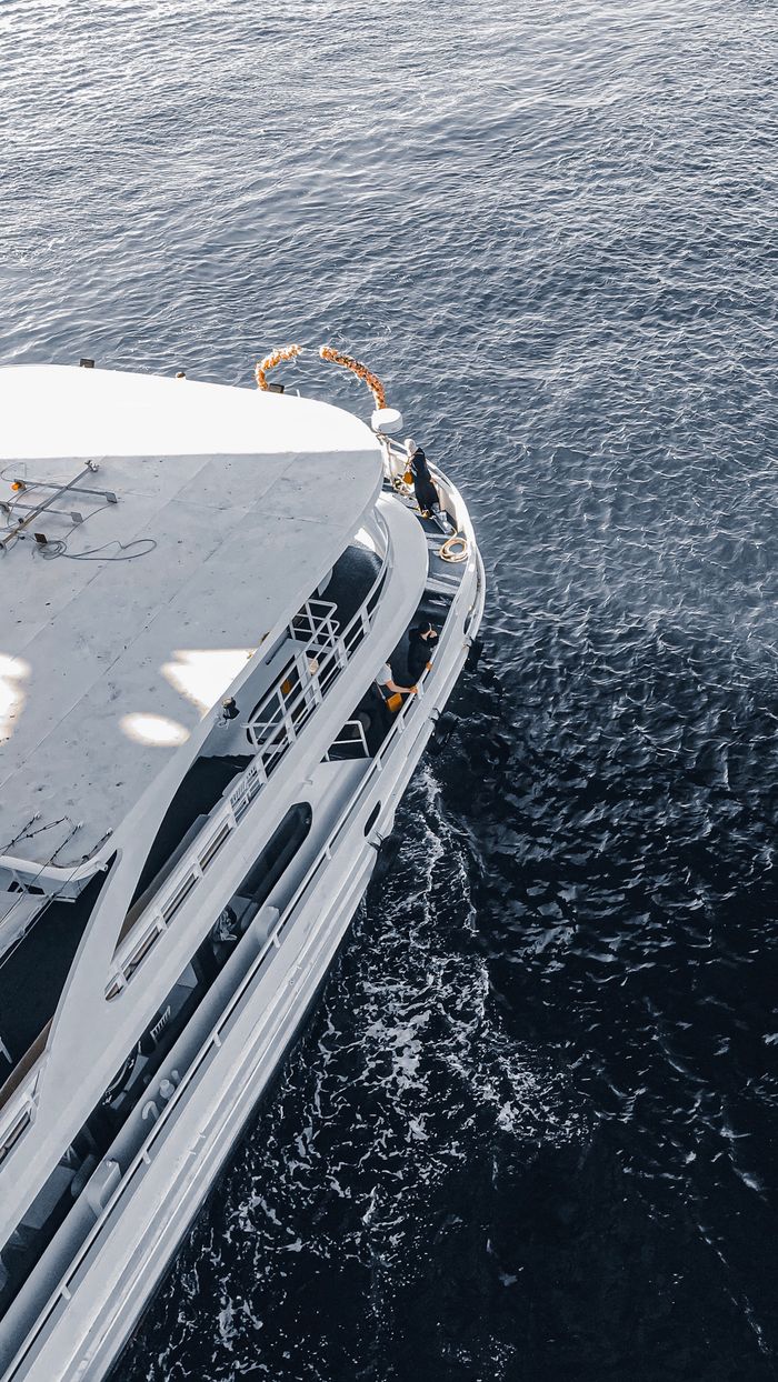 our-story High angle view of a white passenger ship sailing through deep blue waters, showcasing luxury travel.